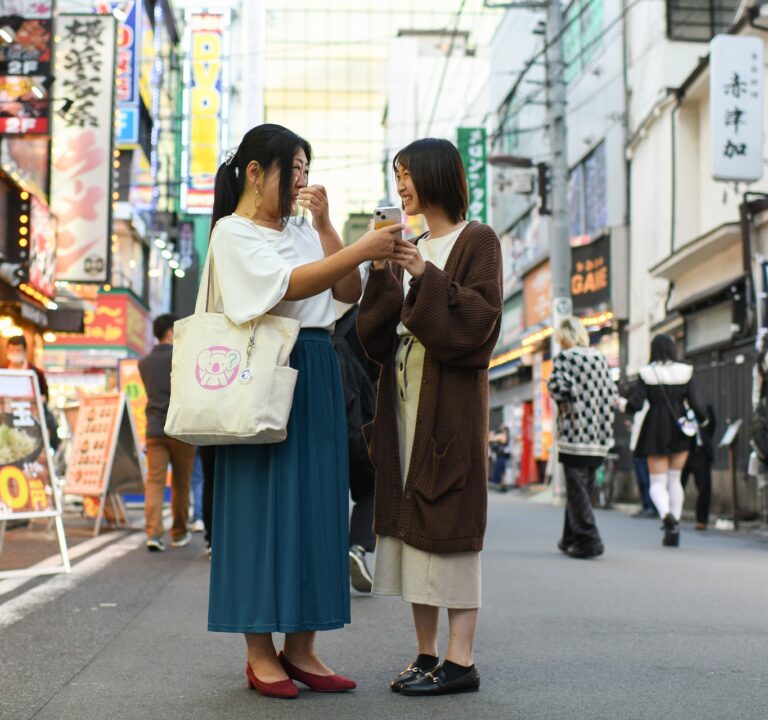 Photo of two women conversing while standing in a street in Tokyo, Japan