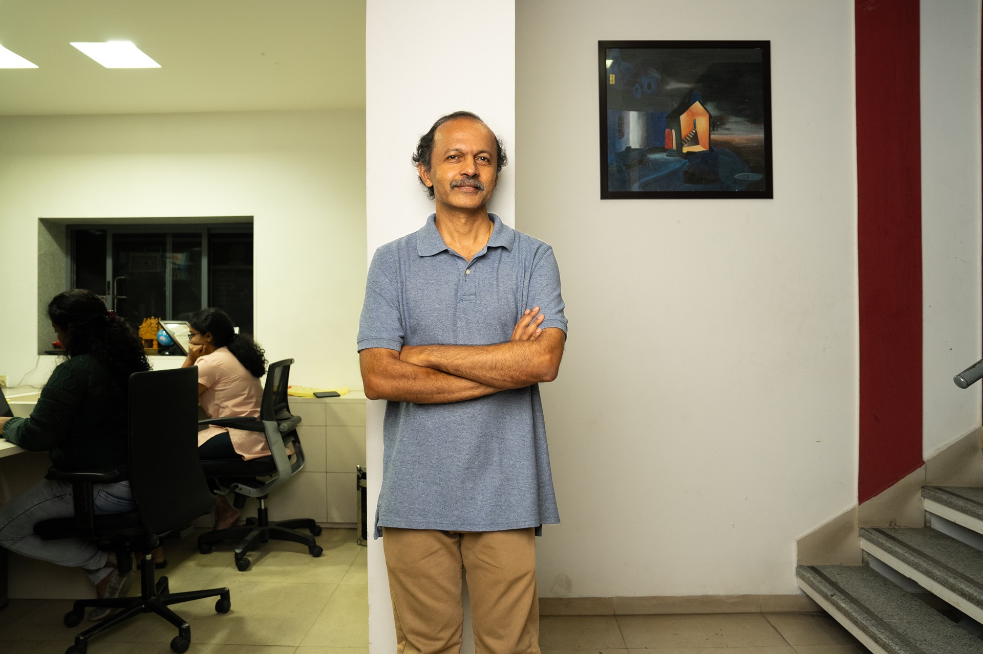 A man standing with arms crossed in an office