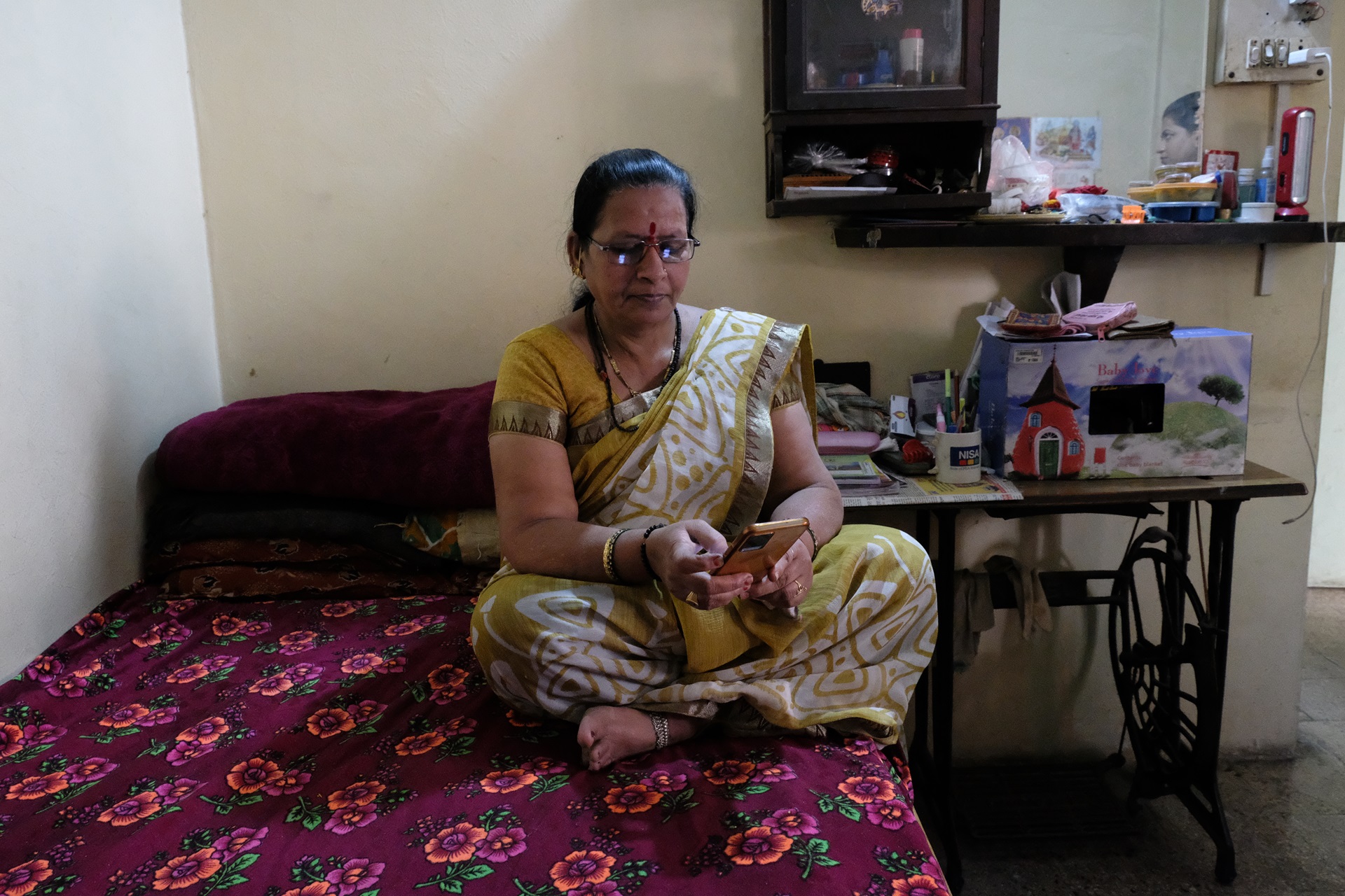 A woman sitting on a bed, looking at her smartphone