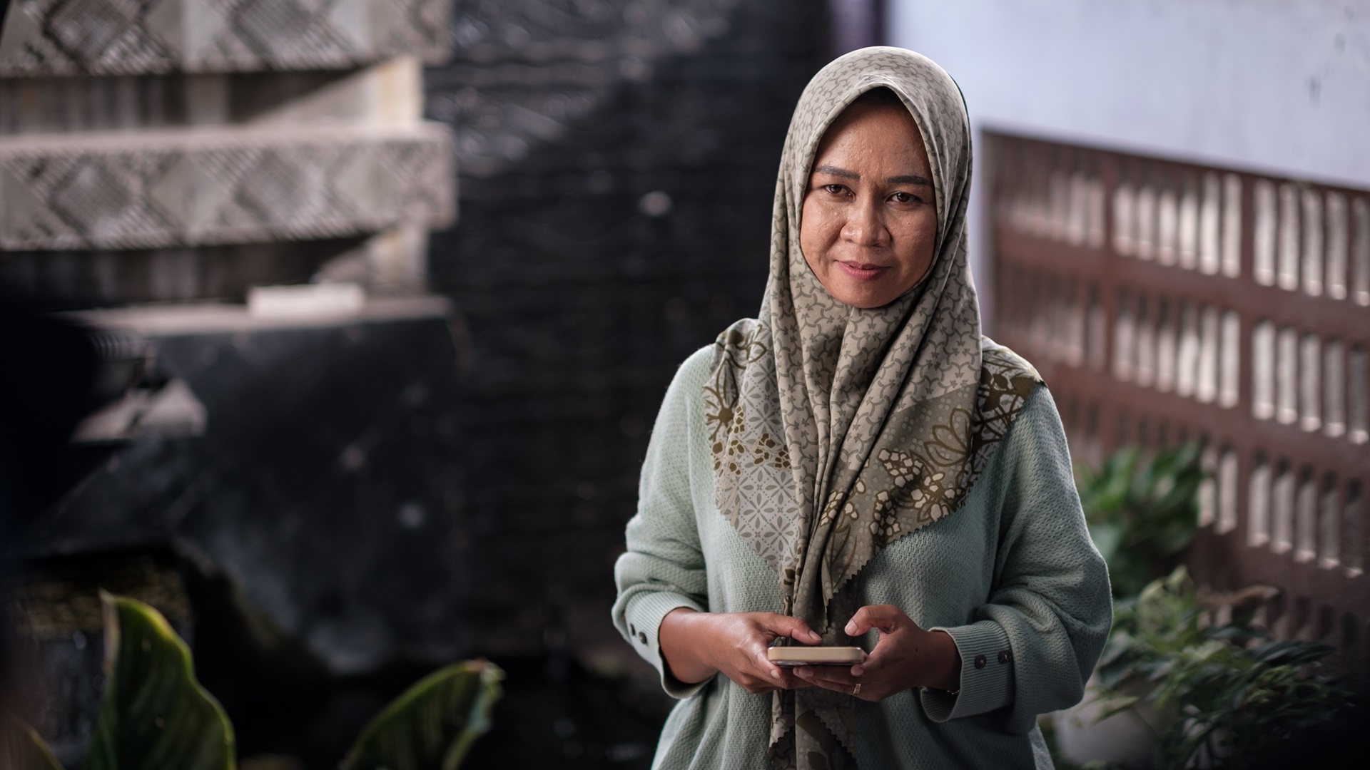 Woman in a headscarf, holding a phone