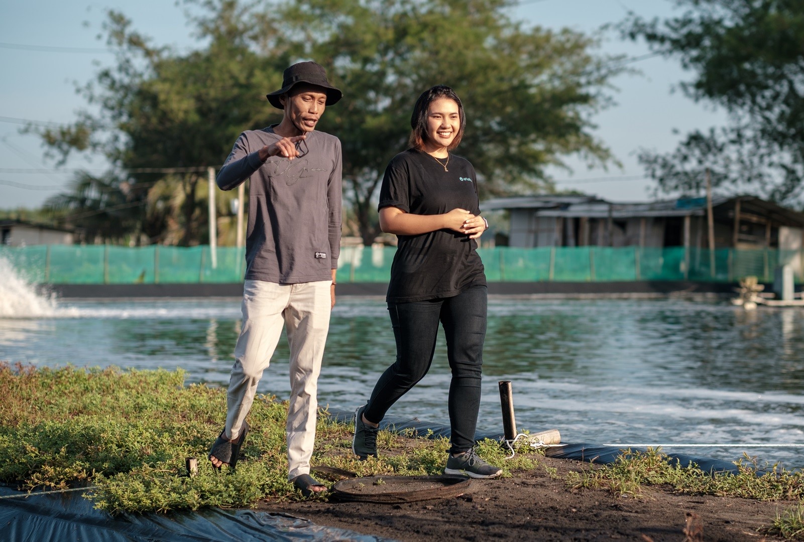 A man and woman walking along a pond in an aqua farm