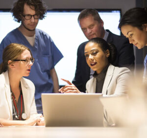 Group of medical staff in discussion at a laptop