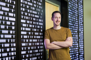 A man with cross arms leaning against a digital wall