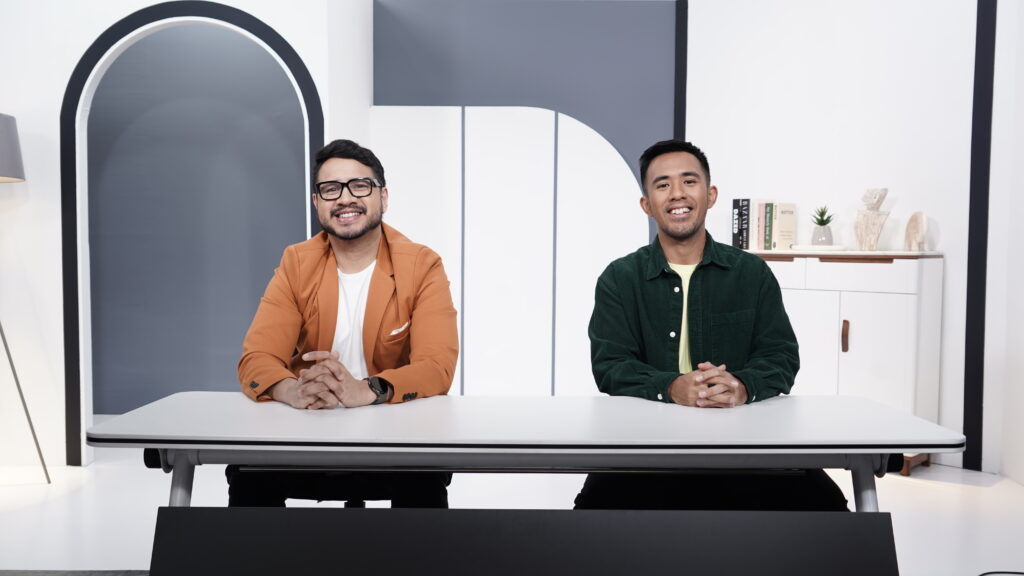 2 men smiling, sitting in front of a table