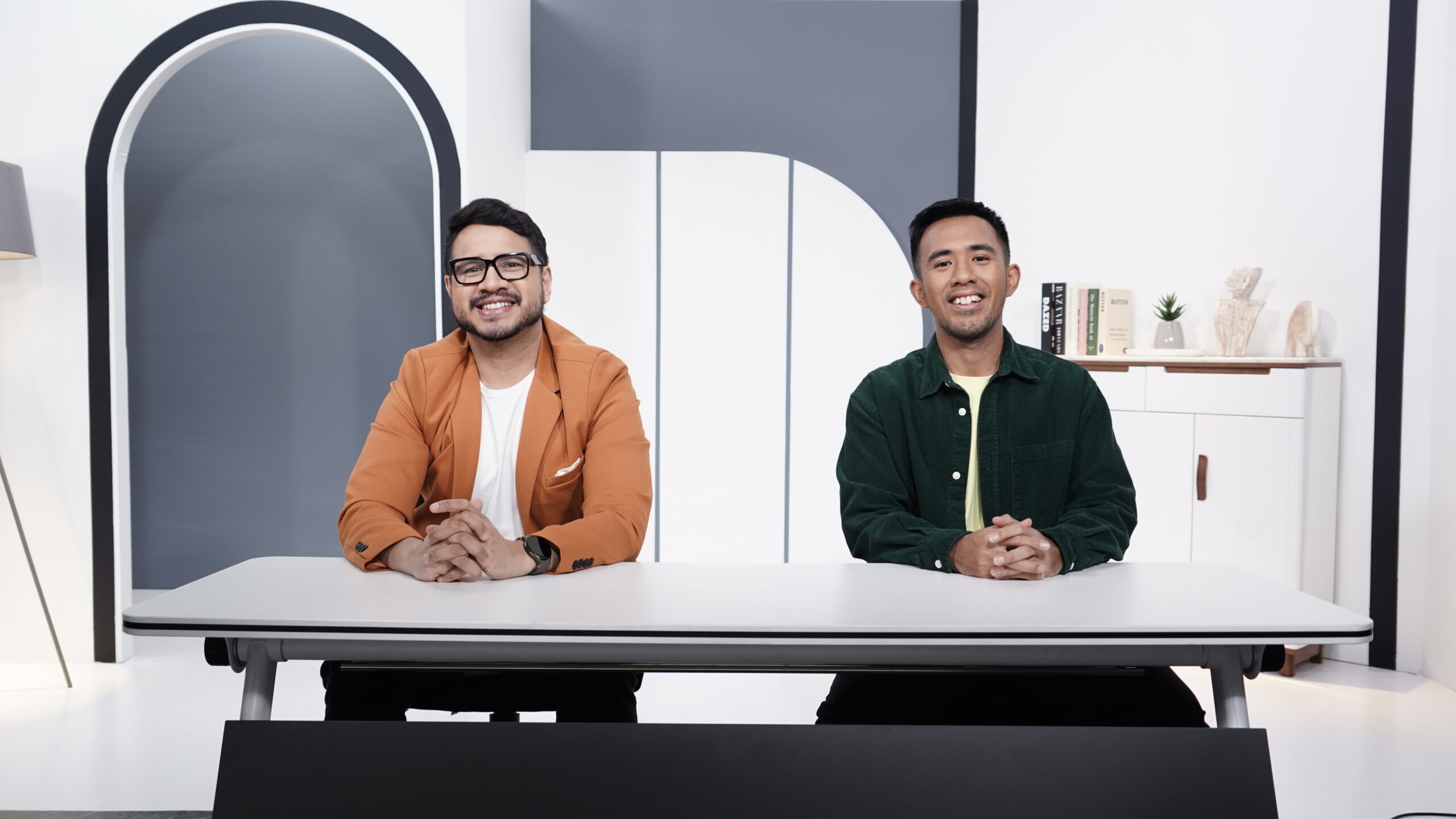 2 men smiling, sitting in front of a table